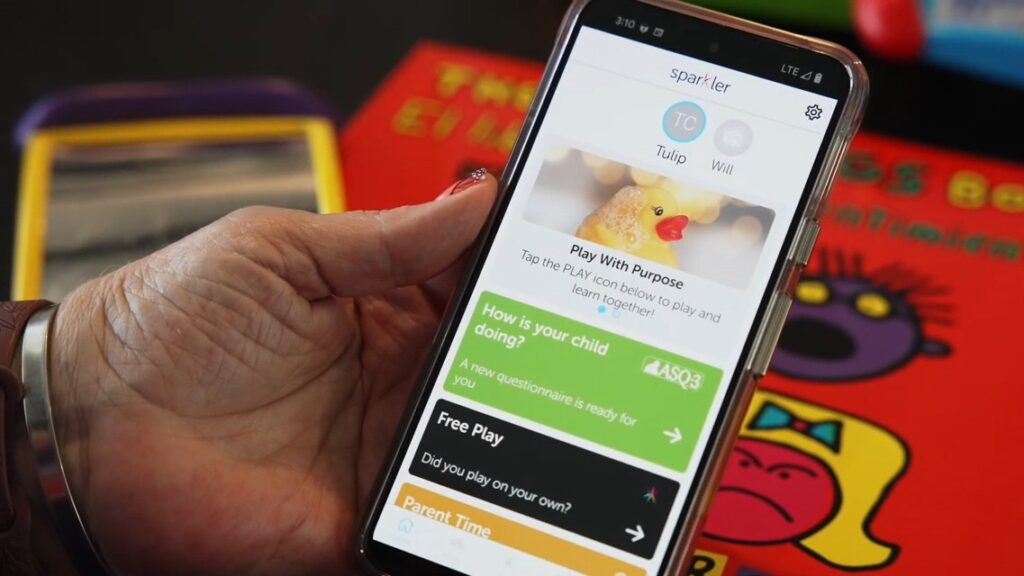 A photo showing a hand holding a mobile phone. The Sparkler app is open on the screen.