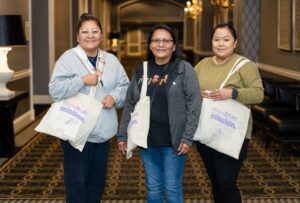 Families Learning Conference attendees pose with their conference tote bags