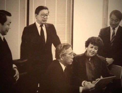 NCFL Founder Sharon Darling sits looking at a document with Dr. Shoichiro Toyoda and other Toyota executives, circa 1990