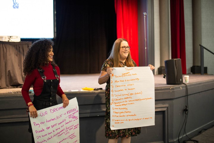 Two NCFL staff members hold large sticky notes with the group's thoughts